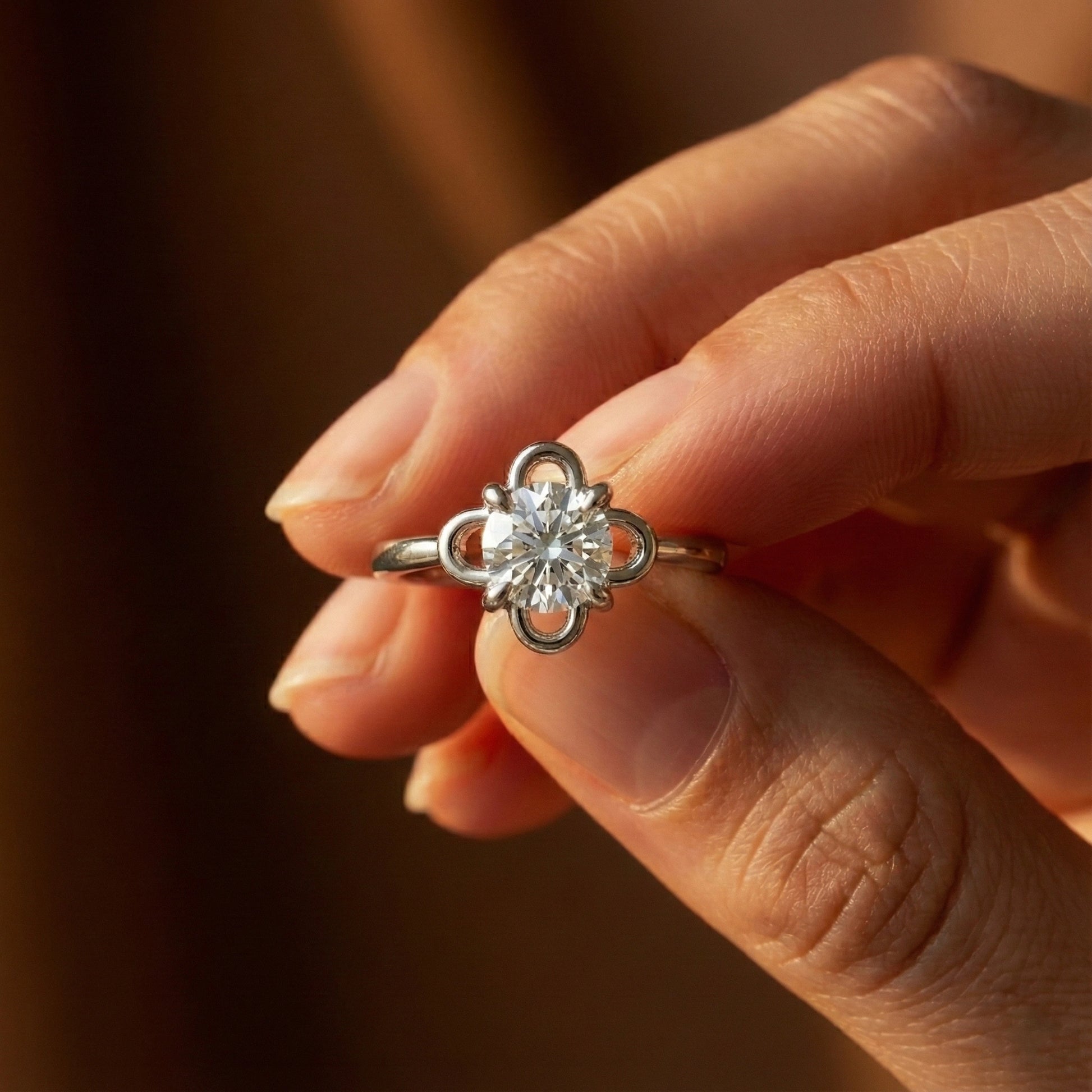 Close-up of a hand holding a diamond ring with a blurred background