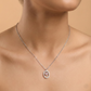 Silver necklace with a pink pendant on a model against a beige background