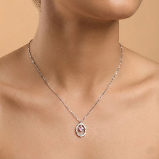 Silver necklace with a pink pendant on a model against a beige background