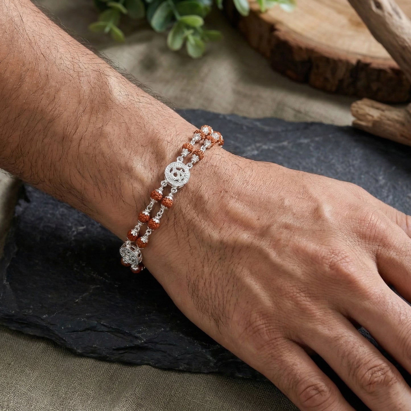 Close-up of silver faith jewellery Om Rudraksha bracelet on wrist