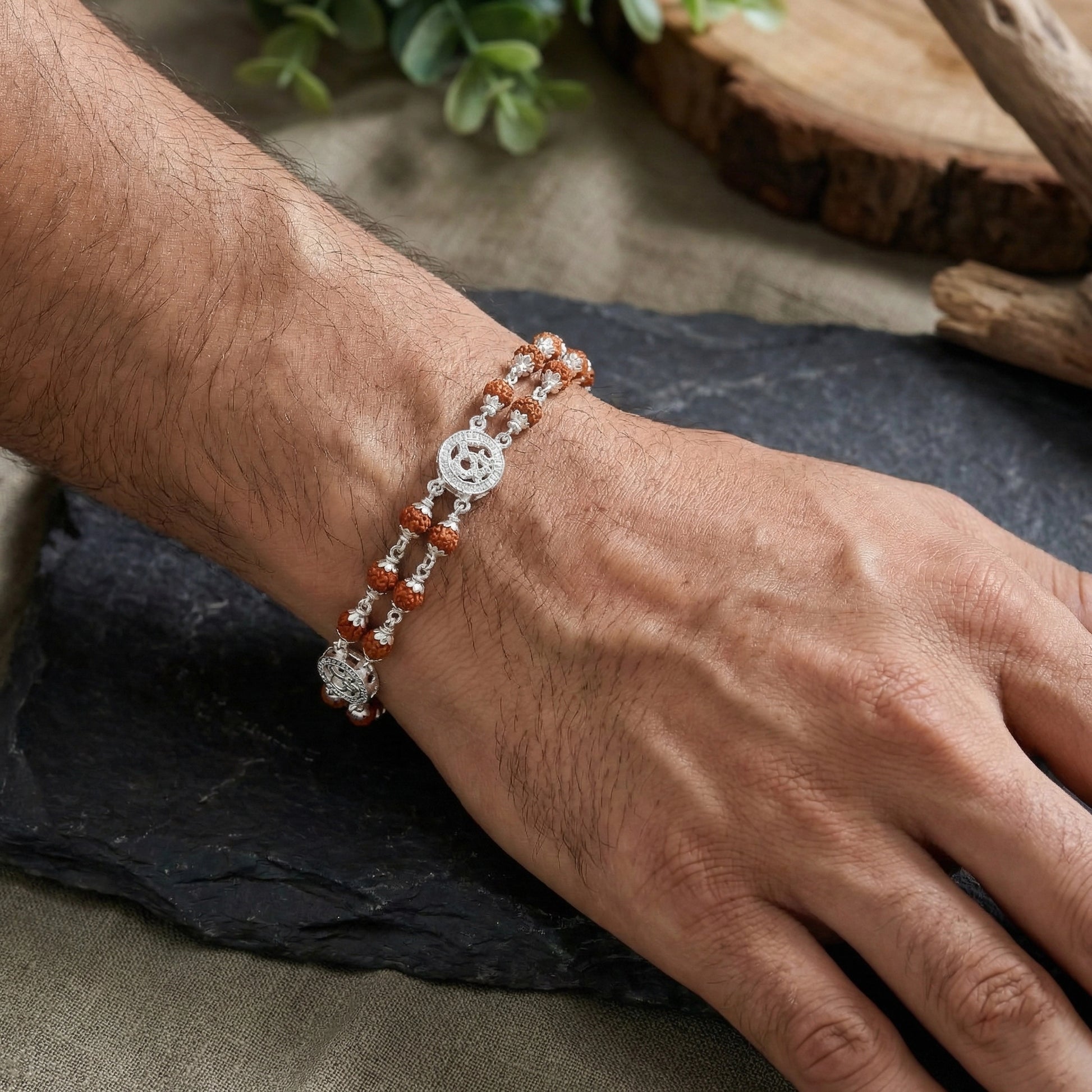 Close-up of silver faith jewellery Om Rudraksha bracelet on wrist
