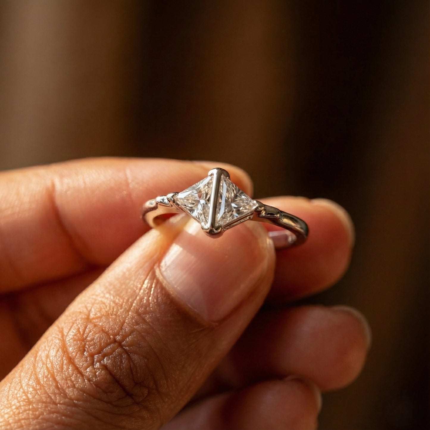 Triangle-cut diamond ring on a finger with a blurred background