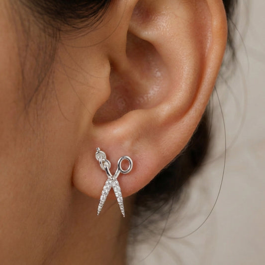 Close-up of an ear wearing silver earrings with a neutral background