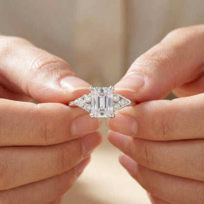 Diamond ring held between two hands against a neutral background