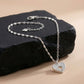 Silver heart-shaped pendant necklace on a dark stone surface