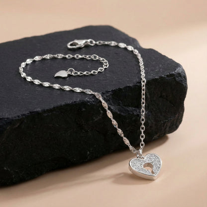 Silver heart-shaped pendant necklace on a dark stone surface