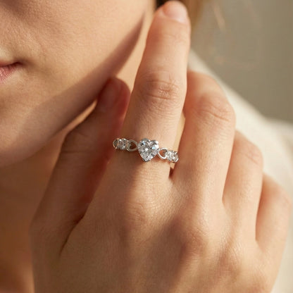Silver ring with heart-shaped gemstones on a hand
