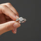 Silver ring with a large diamond held by a hand against a dark background