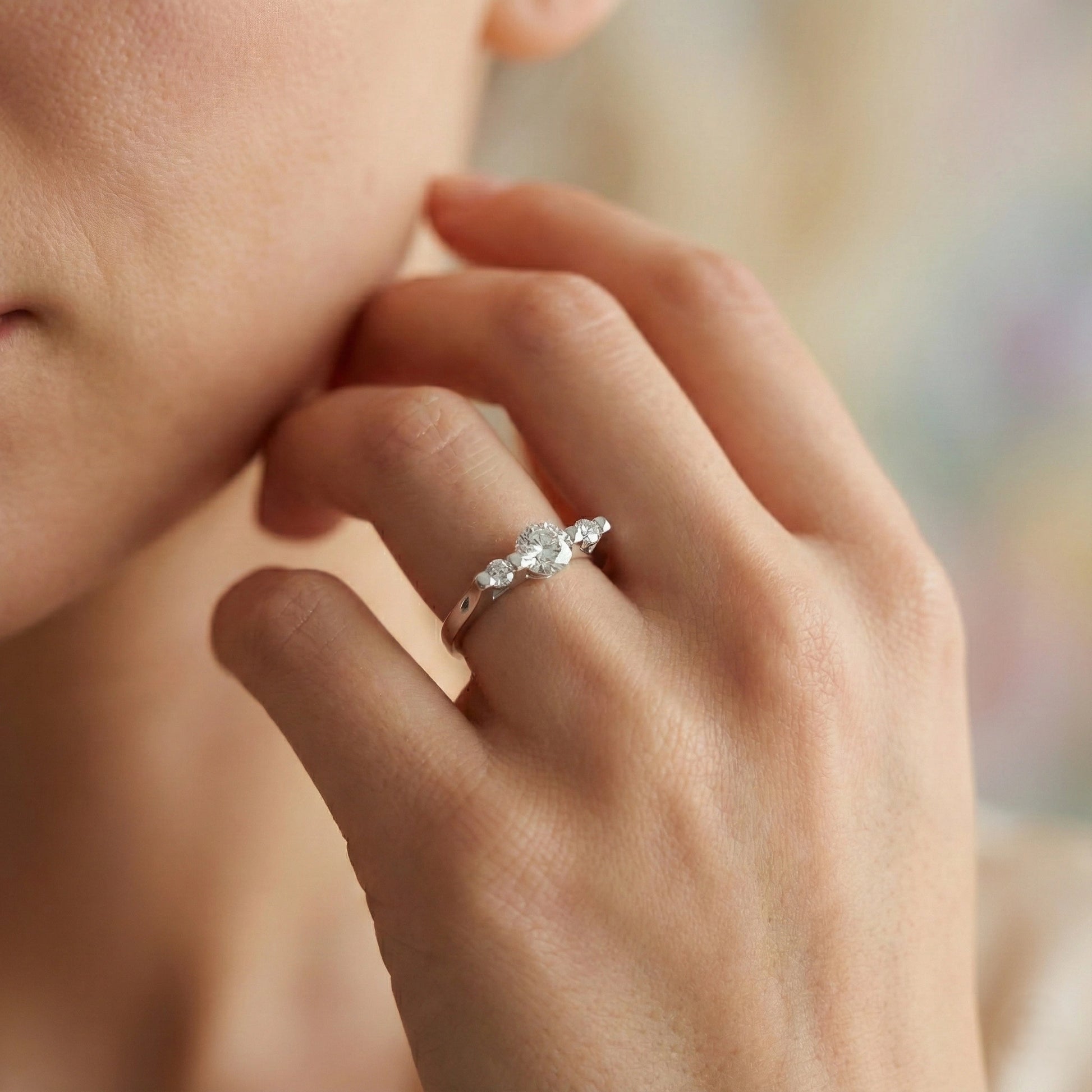 Close-up of a hand wearing a diamond ring with a blurred background