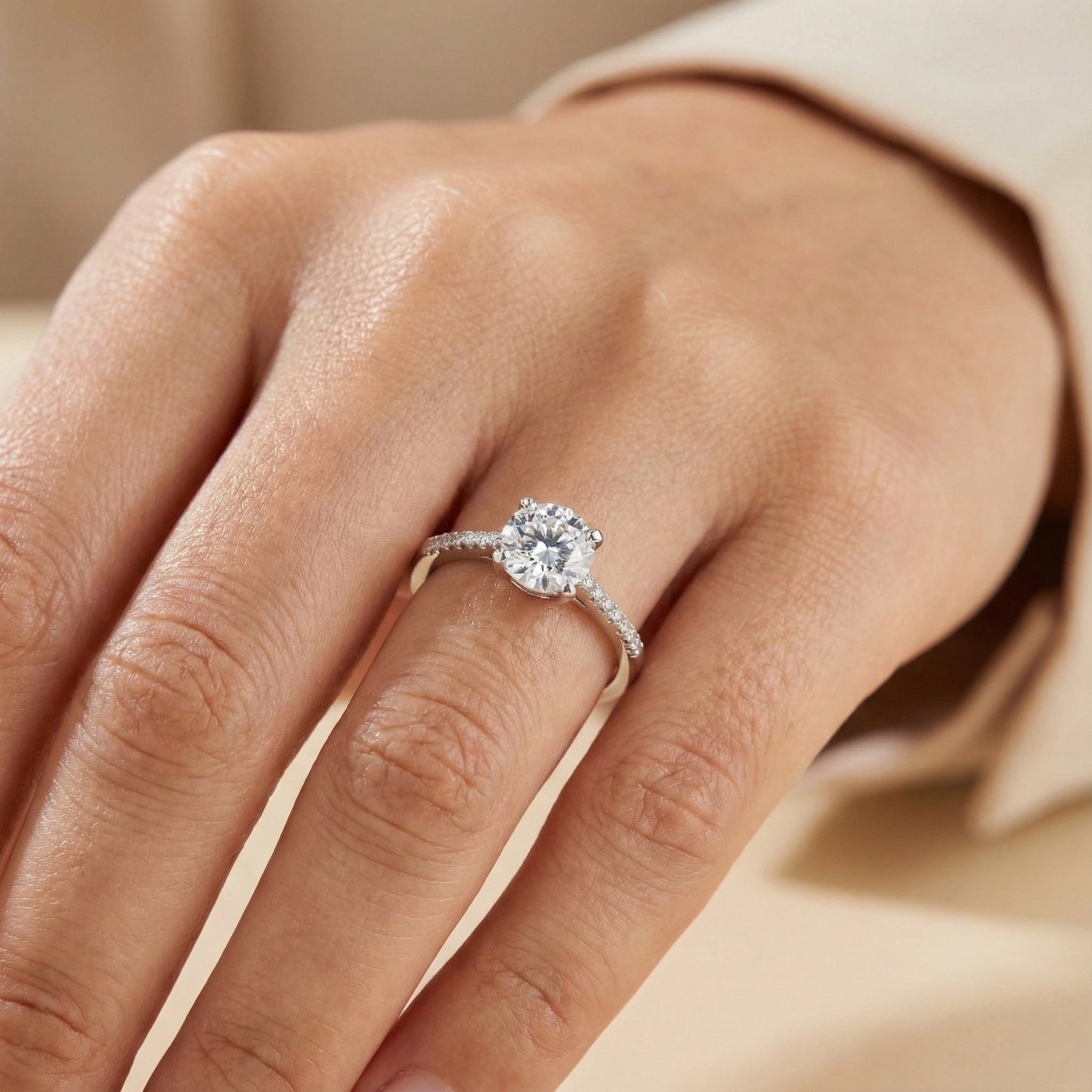 Close-up of a hand wearing a diamond ring on a neutral background
