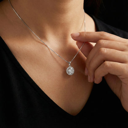 Close-up of a person wearing a silver necklace with a round pendant.
