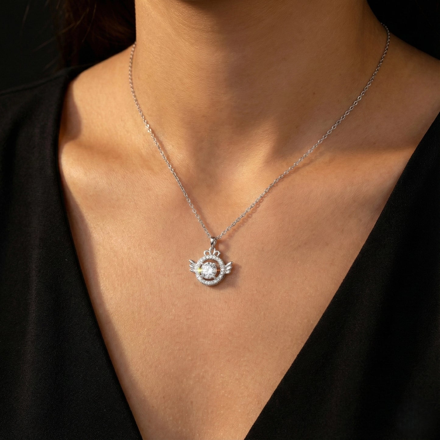 Silver necklace with a pendant worn by a person against a black background