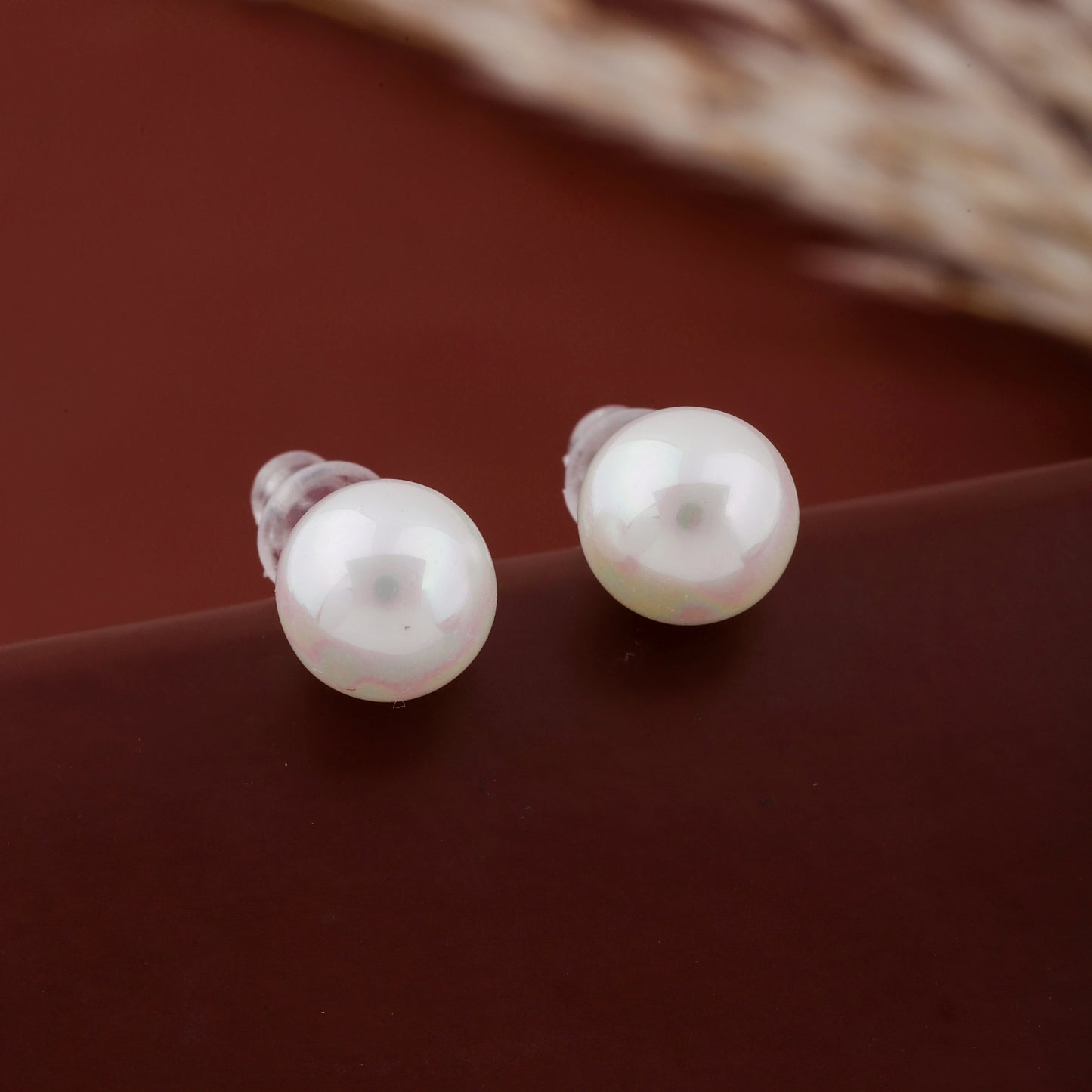 Pair of pearl earrings on a brown surface