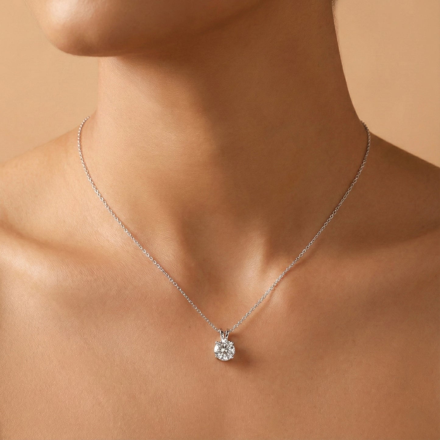 Silver necklace with a diamond pendant on a person's neck against a beige background