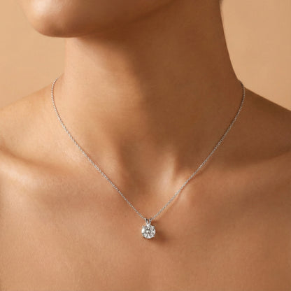 Silver necklace with a diamond pendant on a person's neck against a beige background