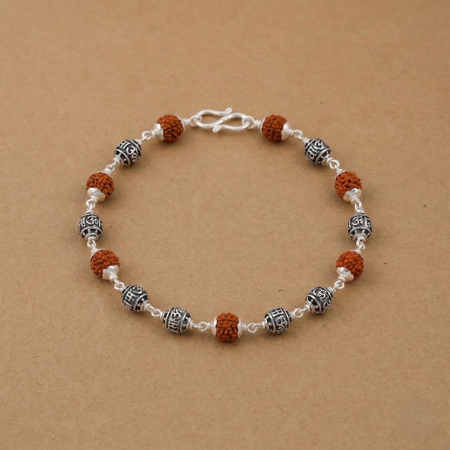 Rudraksha and silver bead bracelet placed on a beige background