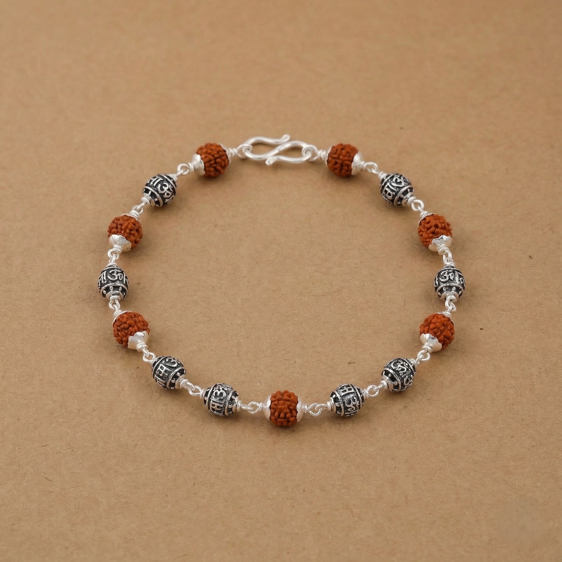 Rudraksha and silver bead bracelet placed on a beige background