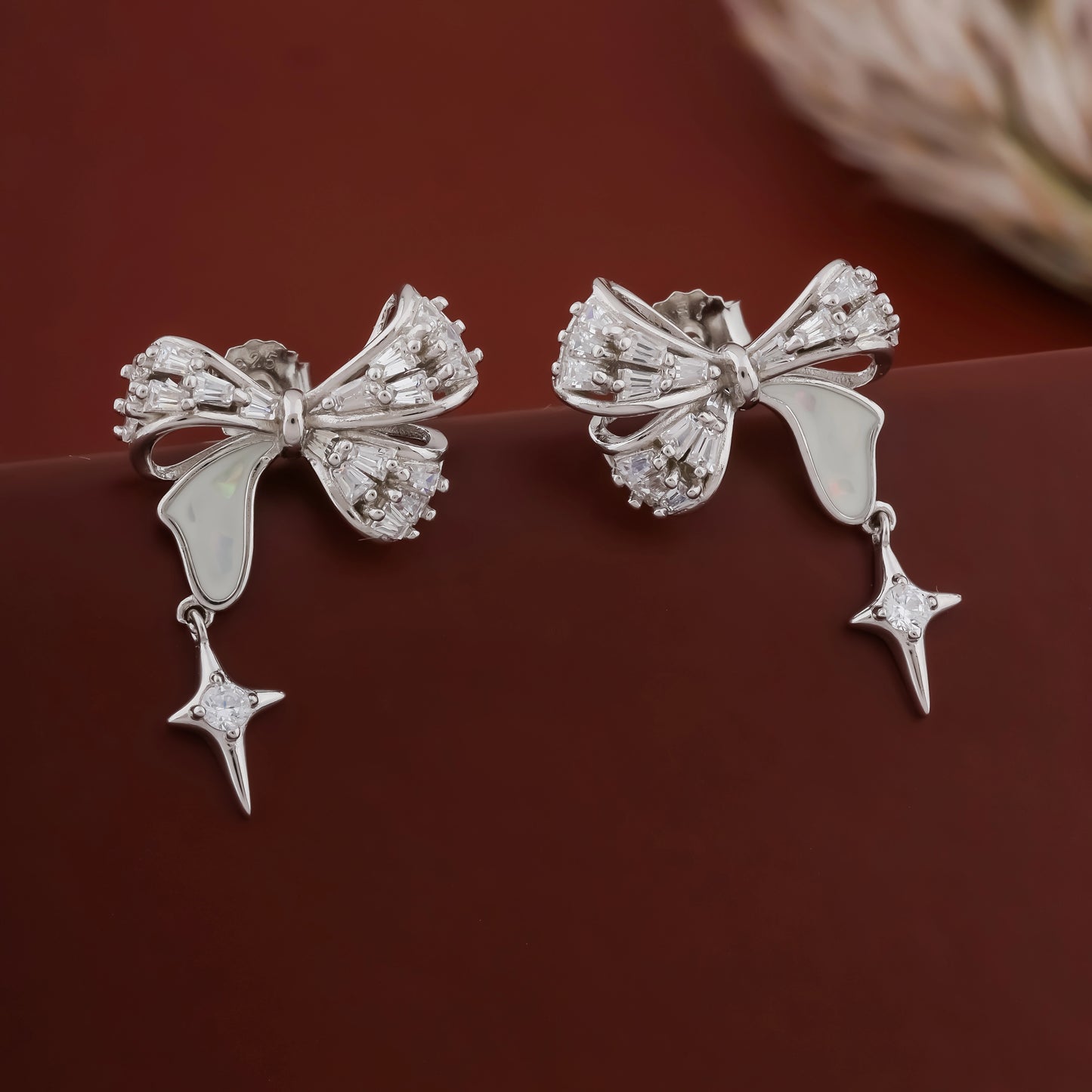 Silver bow-shaped earrings with star details on a dark surface