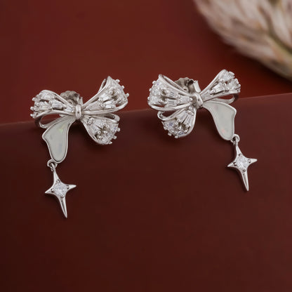 Silver bow-shaped earrings with star details on a dark surface