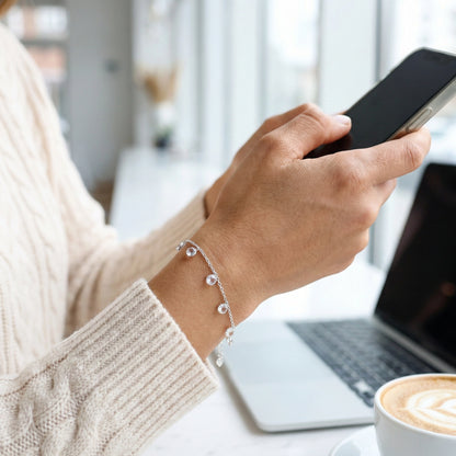 Person using a smartphone with a blurred background of a laptop and coffee cup.