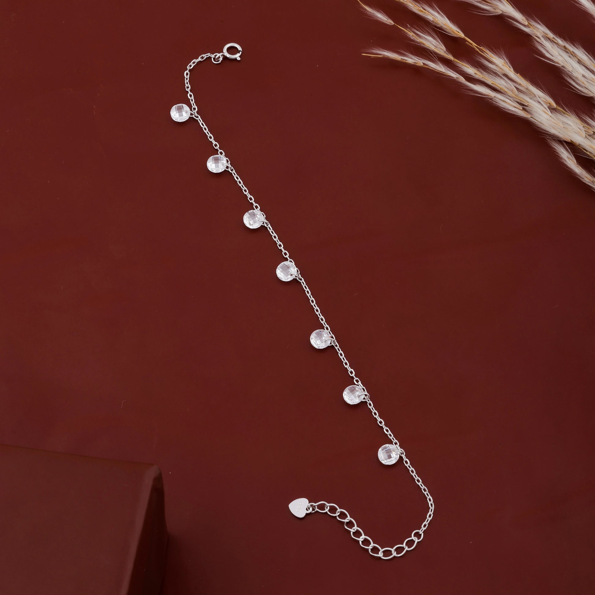 Silver bracelet with small beads on a dark red background