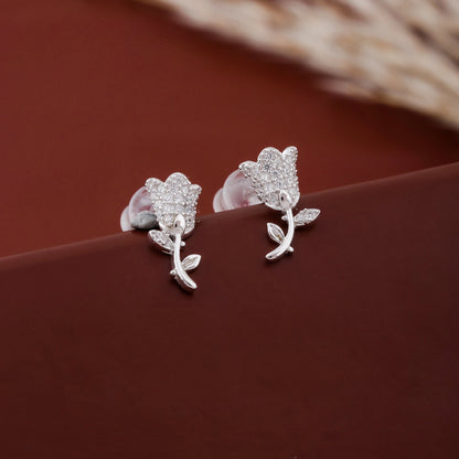 Silver flower-shaped earrings on a brown surface