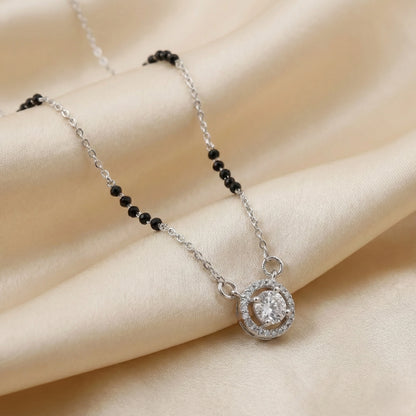 Necklace with a circular pendant and black beads on a beige fabric background