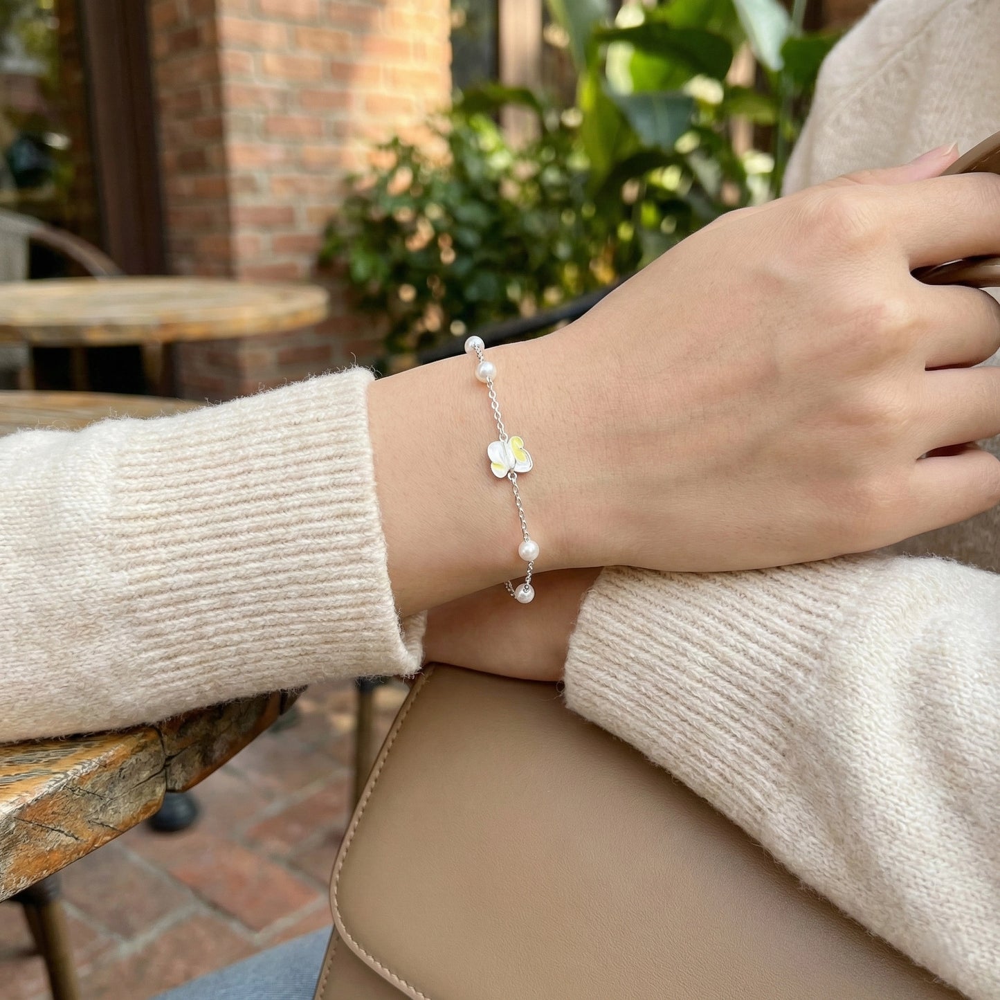 Minimal silver bracelet featuring pearls and butterfly detail