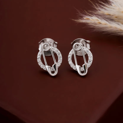 Silver safety pin earrings with clear stones on a brown background
