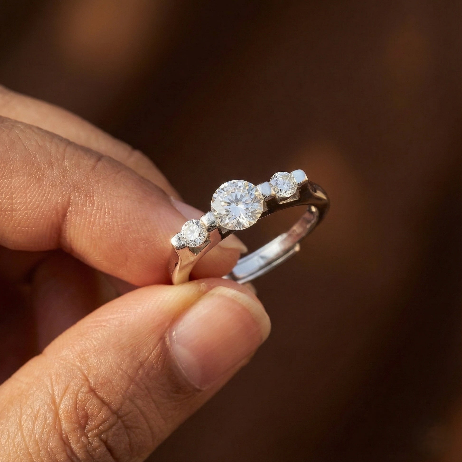 Diamond ring held between fingers against a blurred background