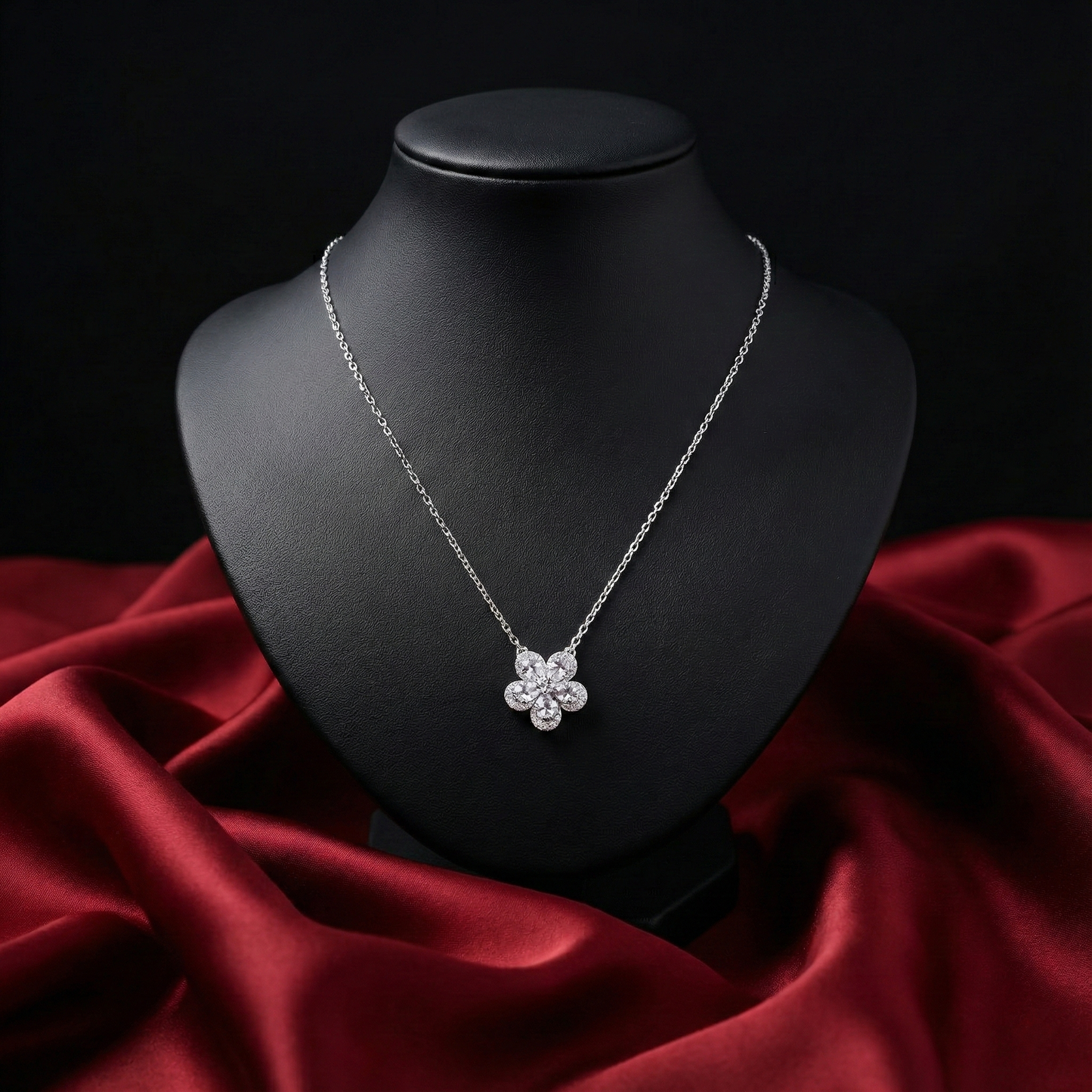 Silver necklace with a floral pendant on a black mannequin bust against a red fabric background
