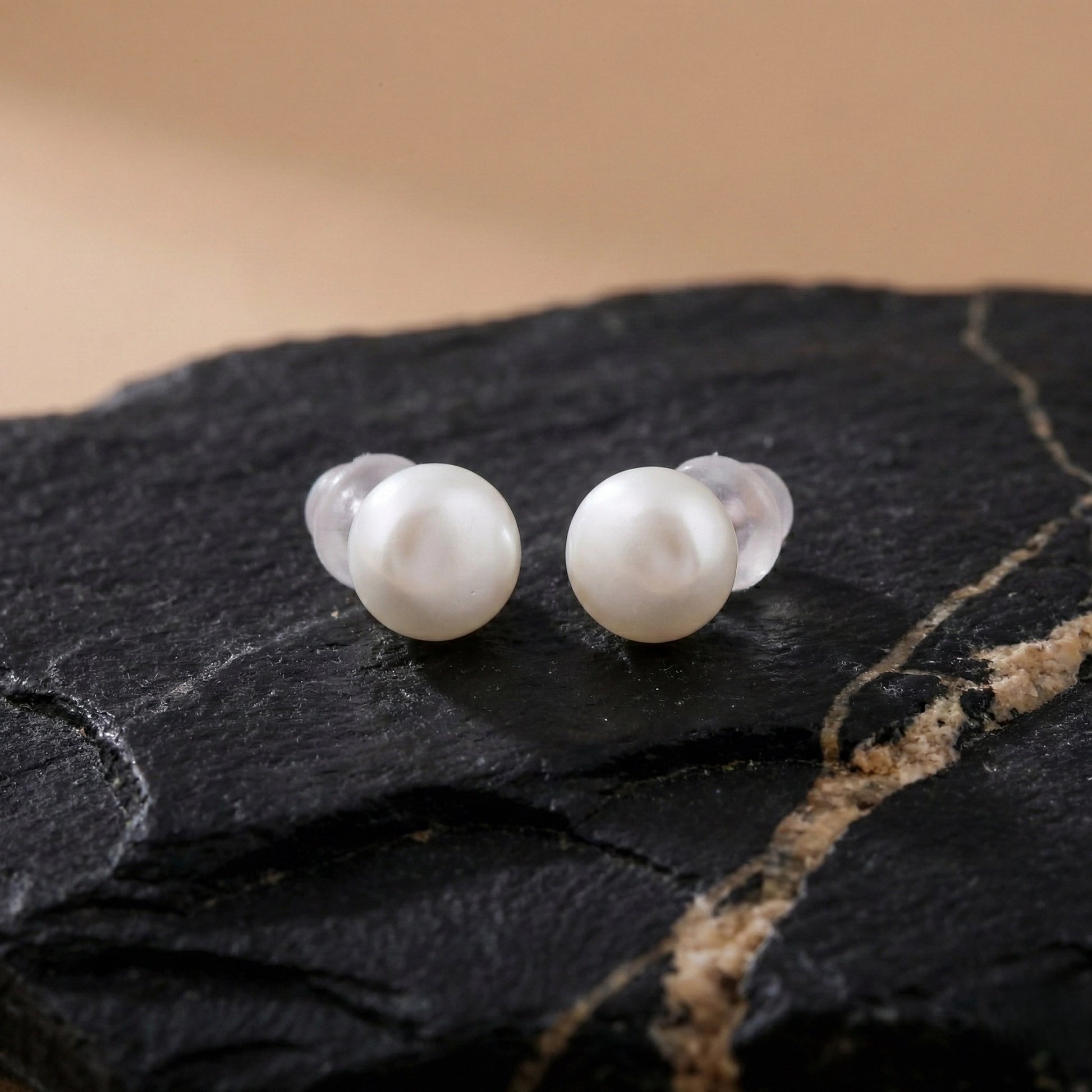 Minimalist pearl stud earrings showing glossy surface and soft reflections