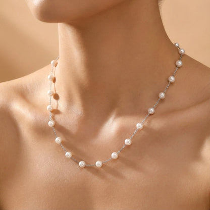 Pearl necklace on a person's neck against a neutral background