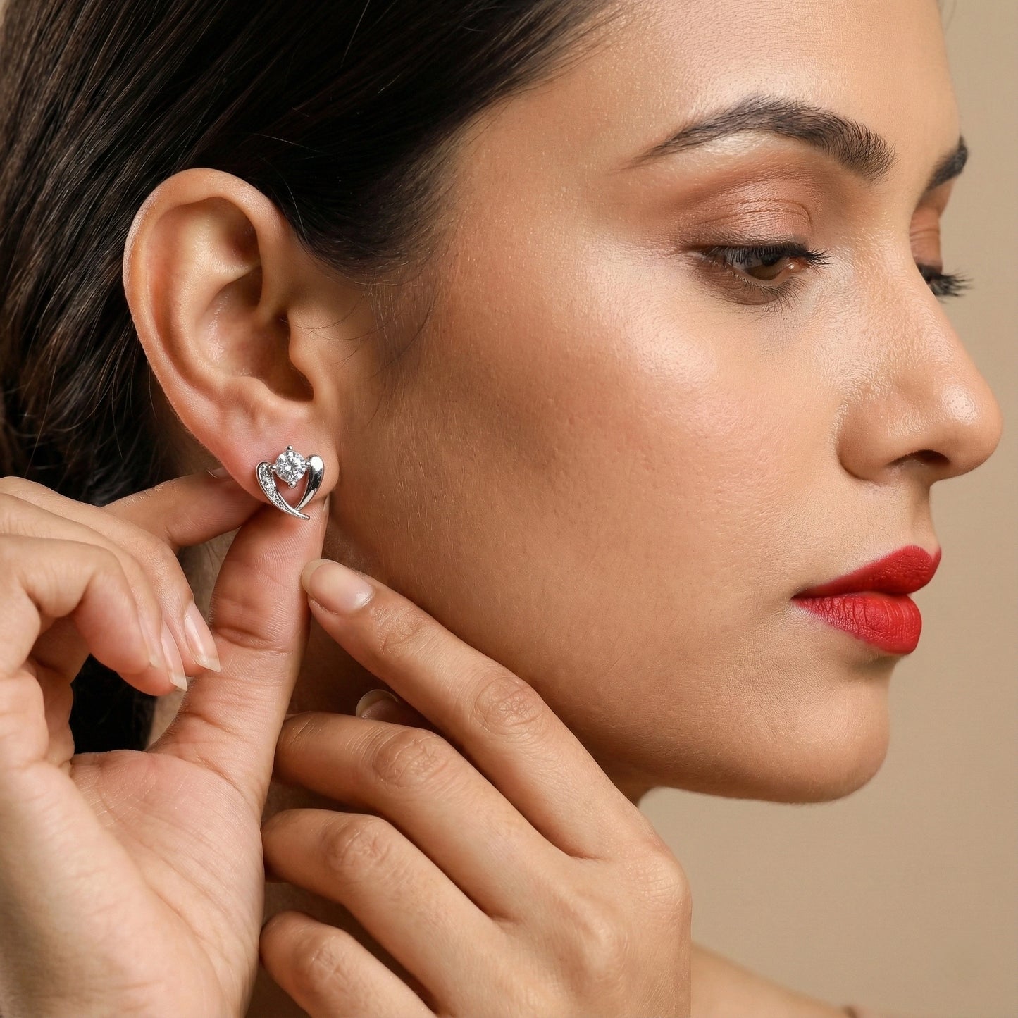 Woman wearing a heart-shaped earring with a neutral background