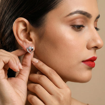 Woman wearing a heart-shaped earring with a neutral background