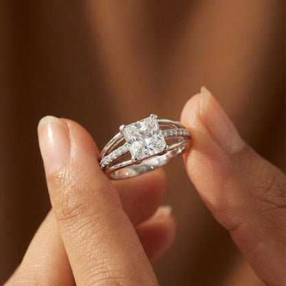 Close-up of a hand holding a diamond ring with a blurred background