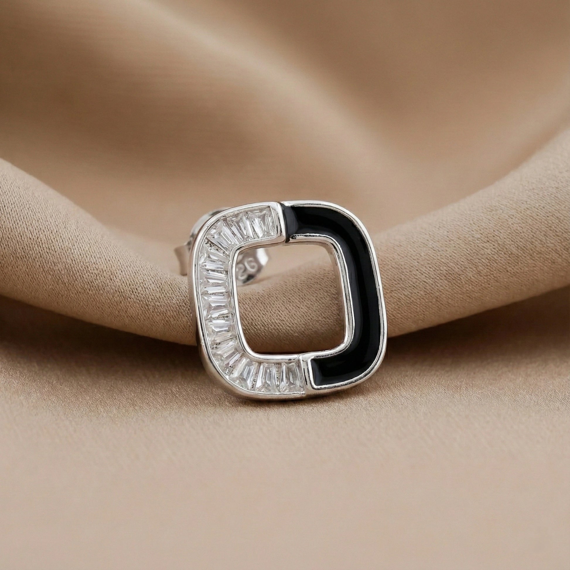 Silver ring with black and clear gemstones on beige fabric