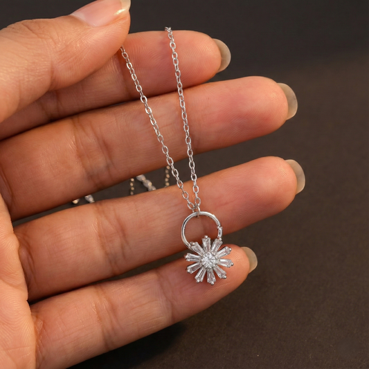 Silver necklace with a star-shaped pendant held by a hand against a dark background