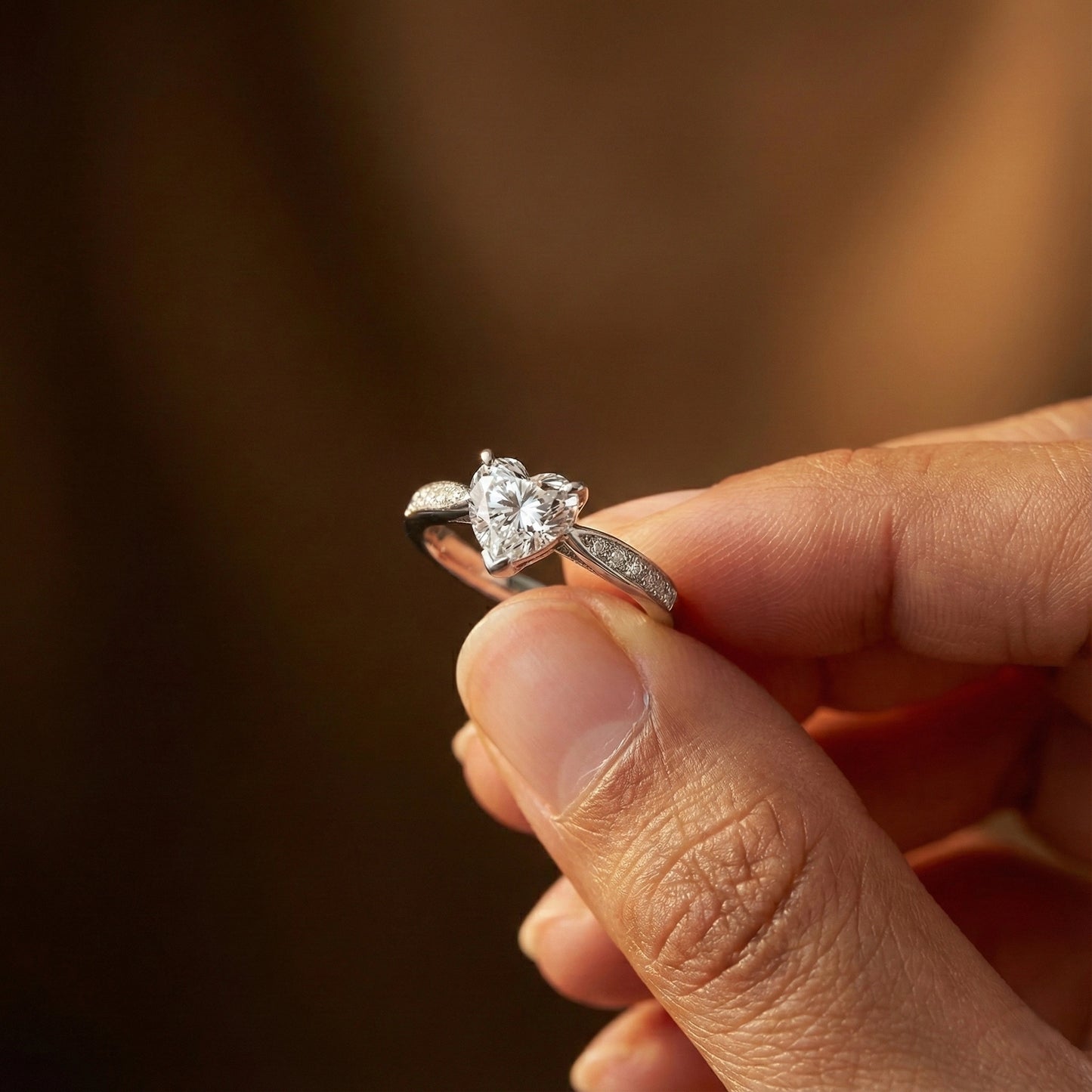 Diamond ring held in a hand with a blurred background