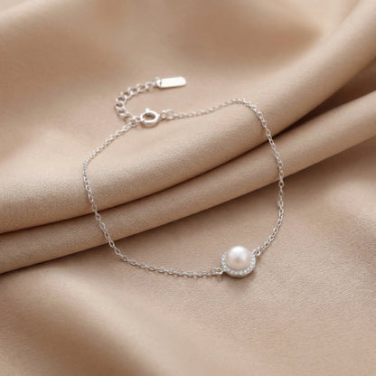 925 silver pearl charm bracelet on beige fabric background