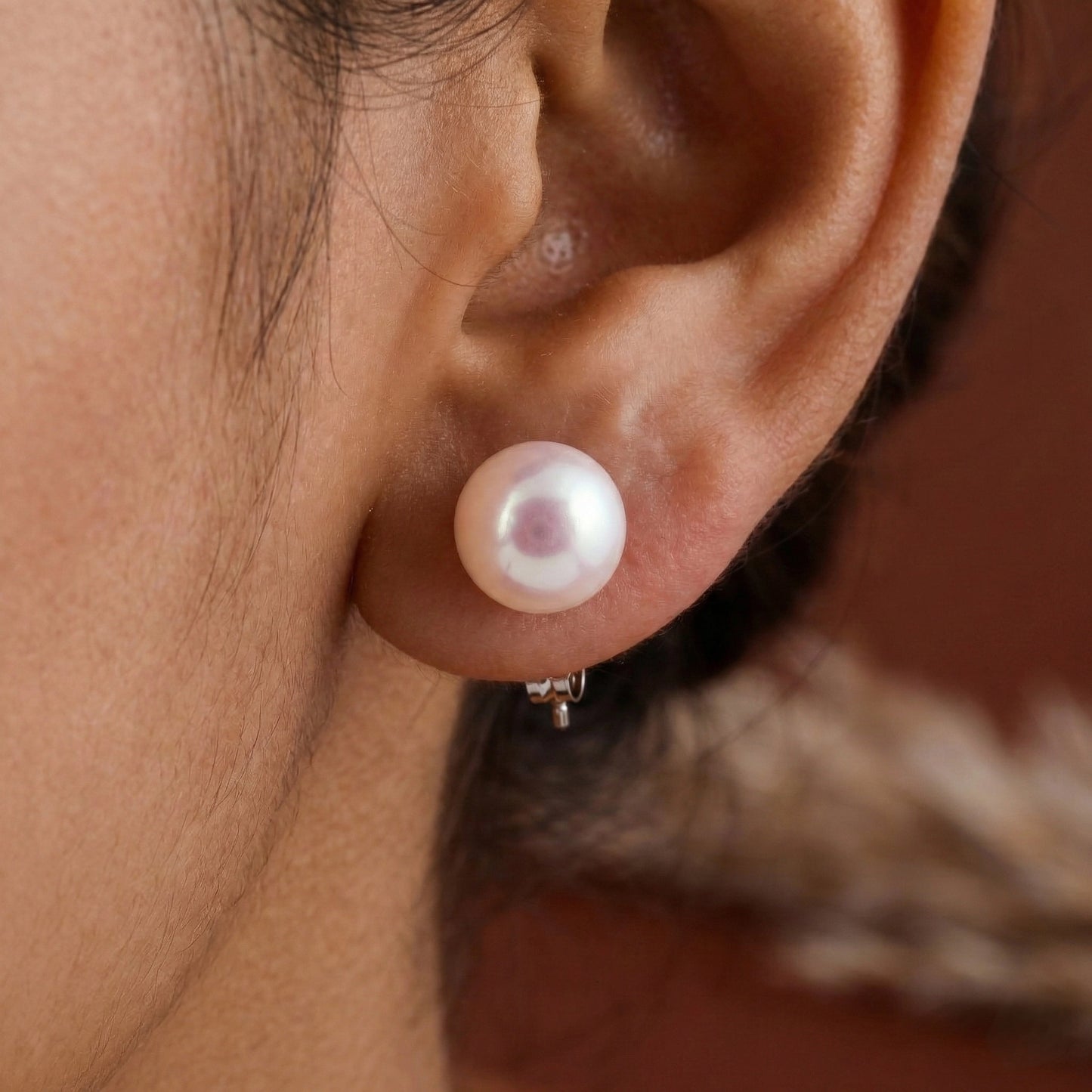 Close-up of an ear wearing a pearl earring with a blurred background