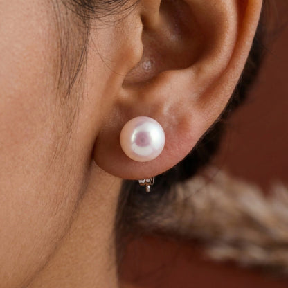 Close-up of an ear wearing a pearl earring with a blurred background