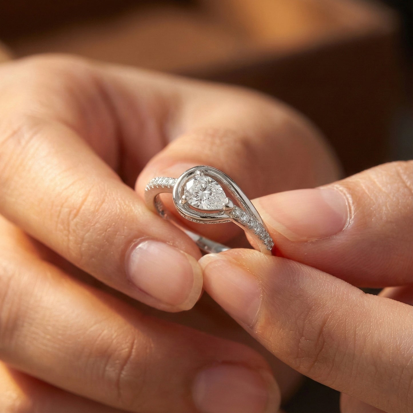 Close-up of a hand holding a silver ring with a diamond.