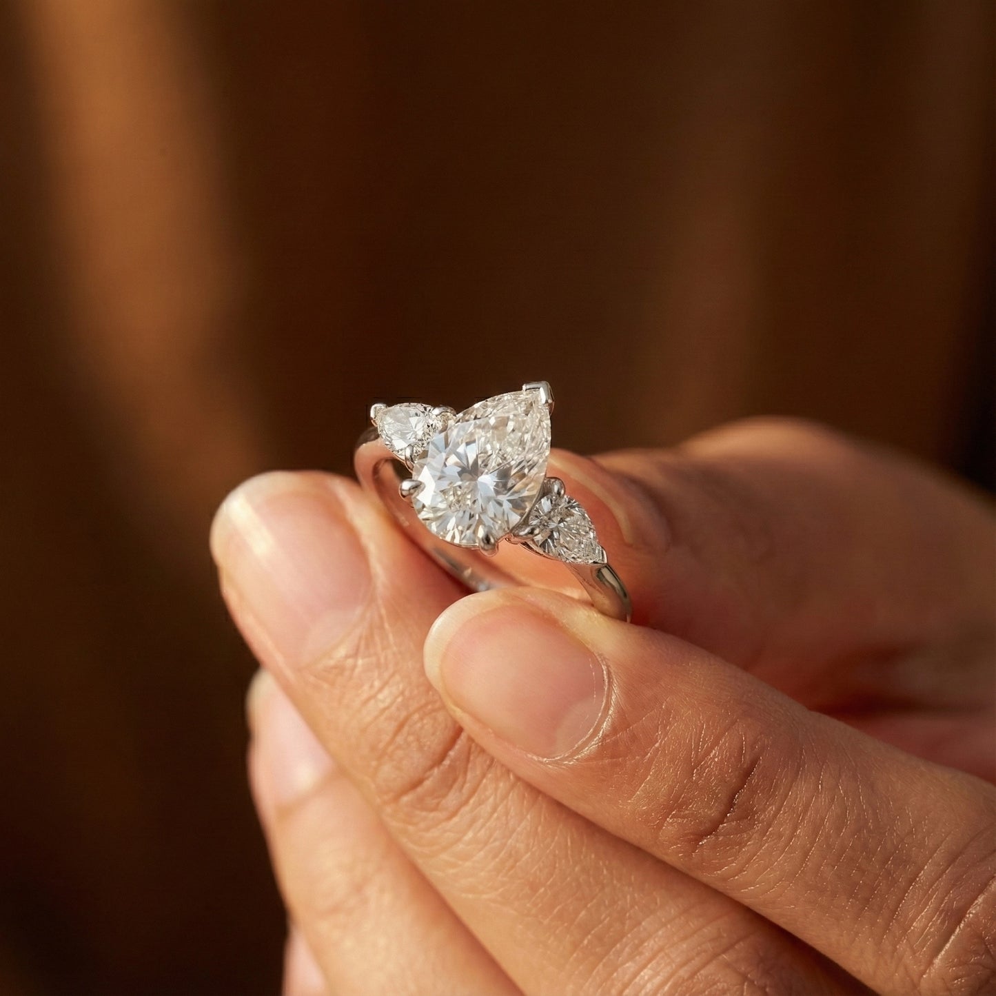 Diamond ring held in a hand with a blurred background