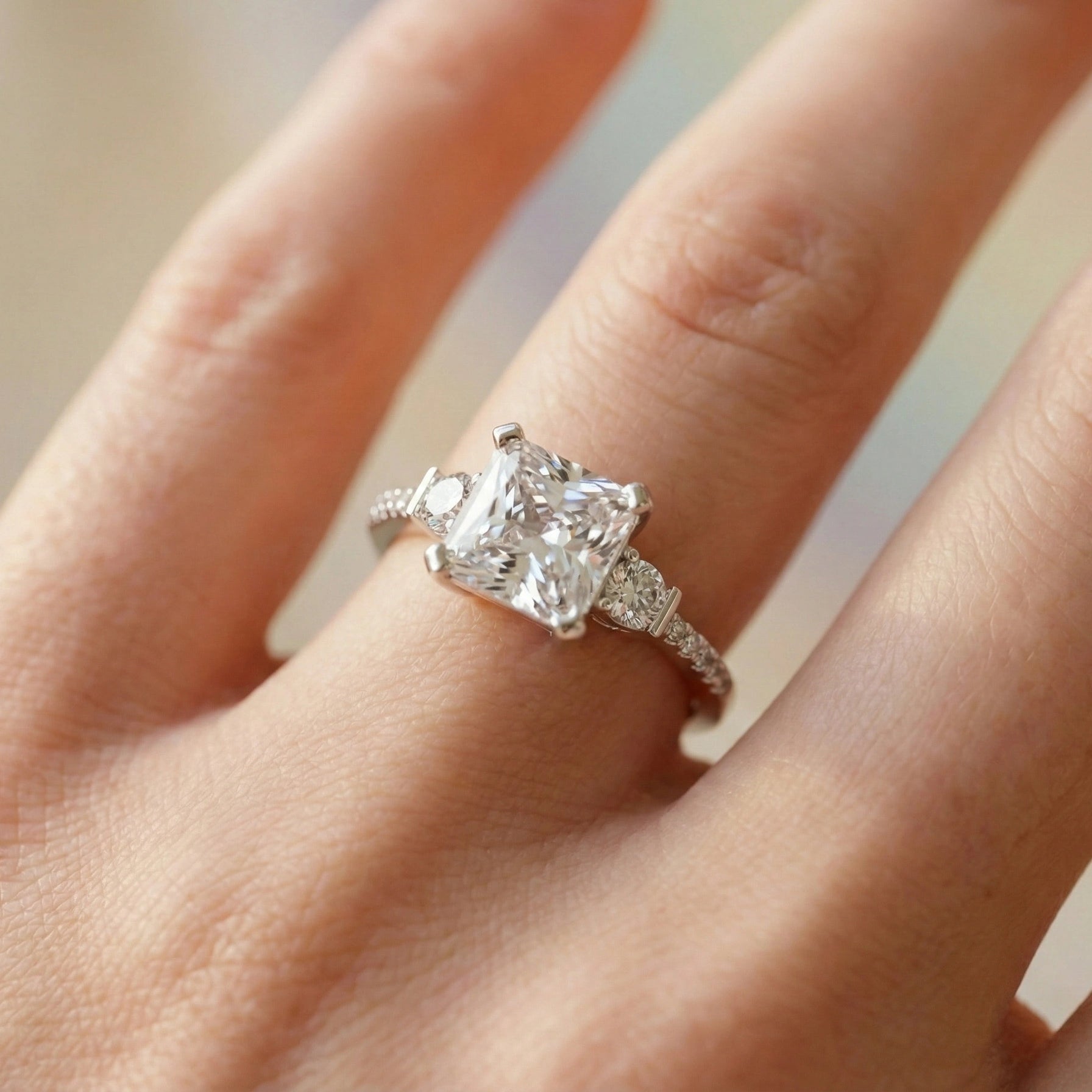 Diamond ring on a finger with a neutral background