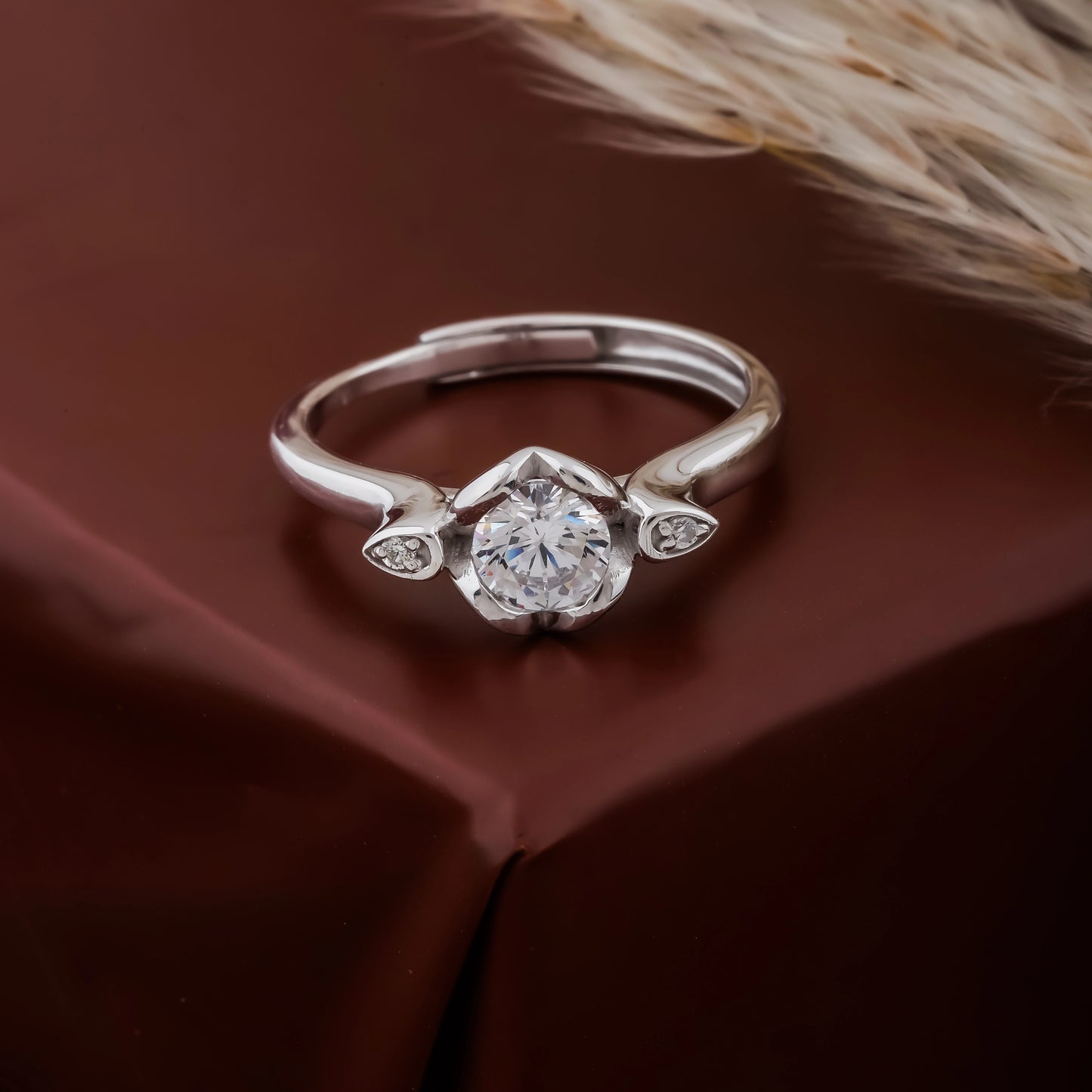 Silver ring with a diamond on a brown fabric background
