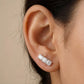 Close-up of an ear wearing a diamond stud earring with a neutral background