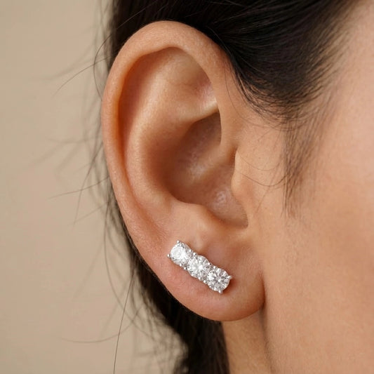 Close-up of an ear wearing a diamond stud earring with a neutral background