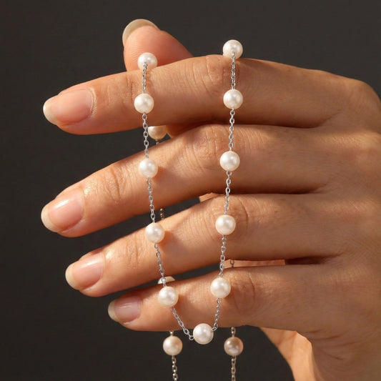 Hand holding a pearl necklace against a dark background