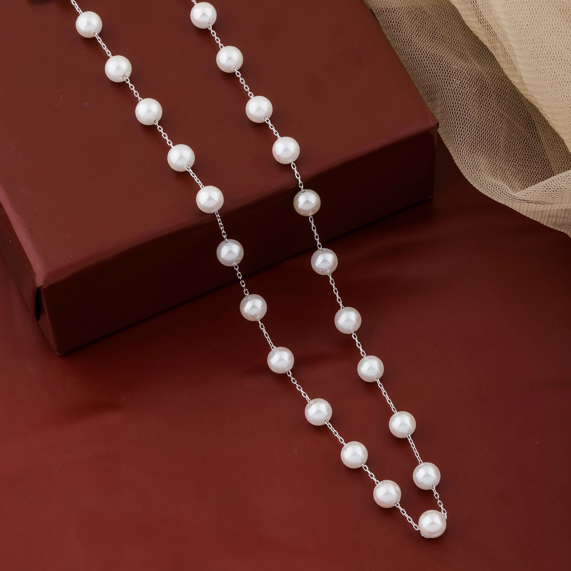 Pearl necklace on a brown surface with a beige fabric background